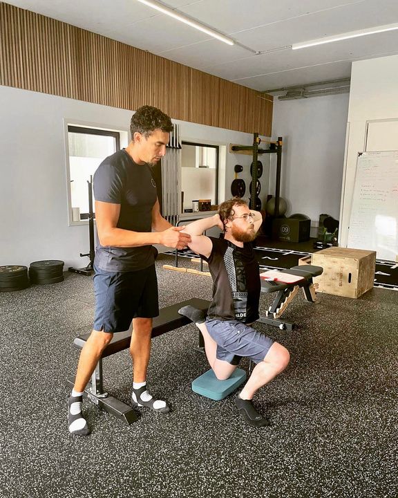 Enis Bedda guiding a client through a mobility exercise in the Synups studio