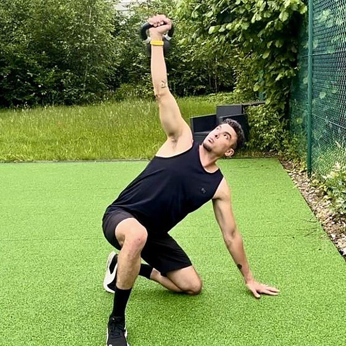 Enis Bedda doing a kettlebell Turkish get-up outdoors